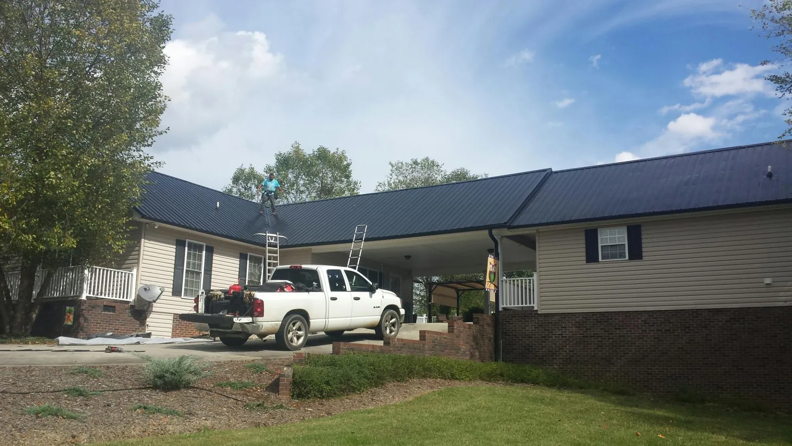 Black metal roof over a home and attached breezeway with ladders set in Belmont